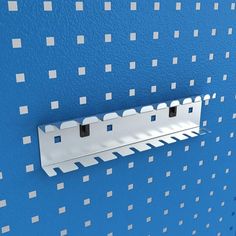 a blue wall with white squares on it and a metal rack attached to the wall