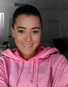 a woman in a pink hoodie smiling at the camera