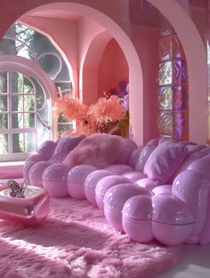 a living room with pink furniture and flowers in vases on the floor next to windows