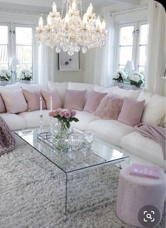 a living room filled with furniture and a chandelier above a glass coffee table