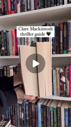 a person is holding a book in front of a bookshelf full of books