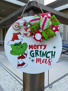 a merry grinch christmas sign hanging on a wooden pole