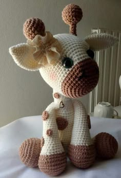 a crocheted giraffe sitting on top of a bed