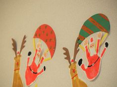 two handprinted reindeers are hanging on the wall next to each other with hats