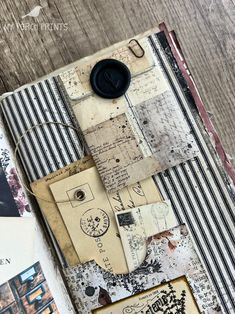 an open book with various papers and buttons on it's cover, sitting on top of a wooden table