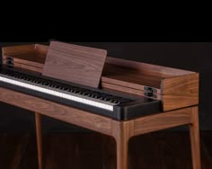 a wooden piano sitting on top of a hard wood floor next to a black wall