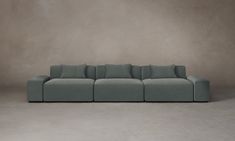 a large gray couch sitting on top of a cement floor next to a white wall