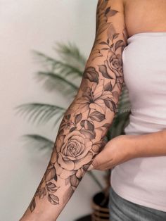 a woman is showing off her arm with flowers on it and leaves around the arm