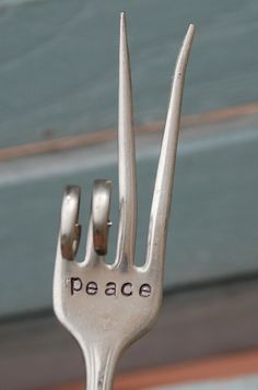 a metal fork with the word peace written on it's side and two forks sticking out of it