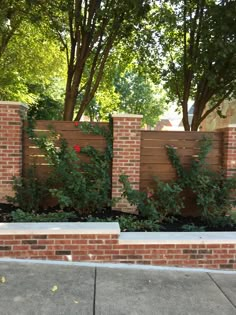 a brick fence with green plants growing on it