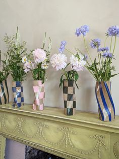 four vases with flowers in them sitting on a mantle