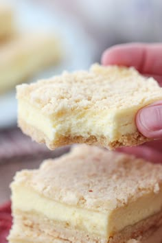 a hand holding two pieces of cake on top of a red plate