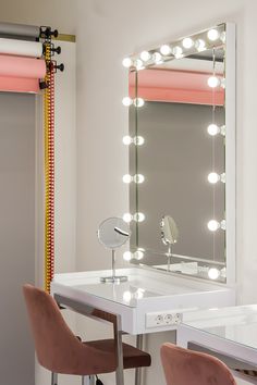 a dressing table with stools and a lighted mirror