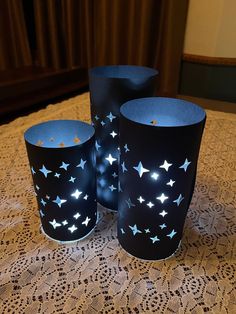 three blue cups sitting on top of a doily covered tablecloth with stars painted on them