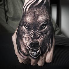 a man's hand with a tattoo of a wolf on it and his face