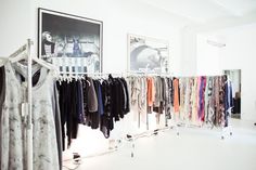 a clothing rack with clothes hanging on it in front of two framed pictures and an art piece