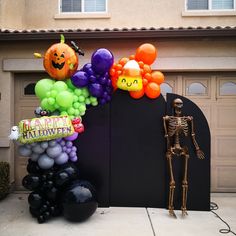 a skeleton is standing next to a bunch of halloween balloons in front of a house