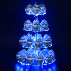 a three tiered cake stand with cupcakes on it and blue lights in the background