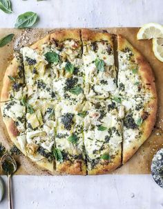 a pizza sitting on top of a cutting board next to sliced lemons and herbs