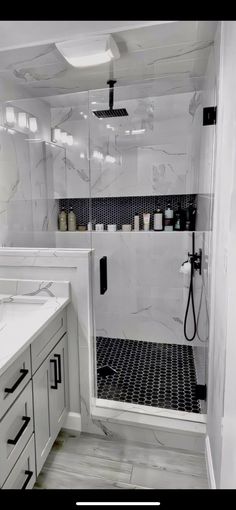 a white bathroom with black and white tile on the shower wall, sink, and mirror