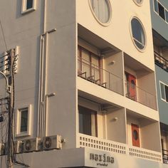 an apartment building with round windows and balconies on the second floor, in front of a traffic light