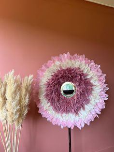 two vases with dried flowers in front of a pink wall, one has a mirror on it