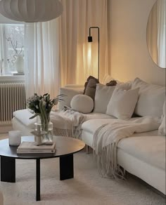 a living room filled with white furniture and flowers on top of a glass coffee table