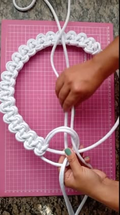 someone is making a heart with white yarn