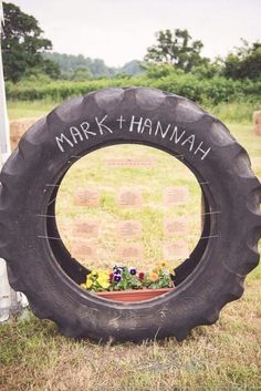 a tire with flowers in it sitting on the ground next to a sign that says mark hannah