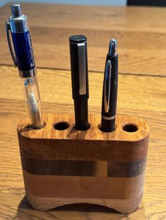 a wooden pen holder with pens on it