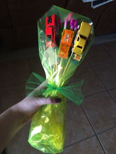 a hand holding a bag filled with different types of toy cars and candy canes