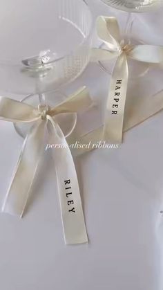 two wine glasses with ribbons tied around them on top of a white table cloth that says happily married