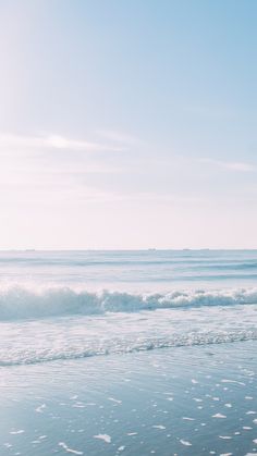 a person walking on the beach carrying a surfboard