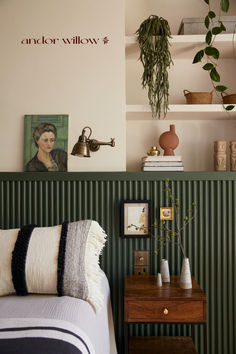 a bedroom with green and white striped walls, potted plants on the shelf above the bed