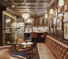 the interior of a bar with leather couches and wine glasses in front of it