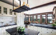 a large kitchen with black counter tops and white cabinets, along with an island in the middle