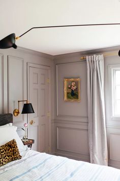 a bedroom with gray walls, white bedding and two lamps on either side of the bed