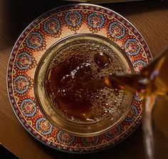 an open book on a table next to a glass bowl filled with liquid