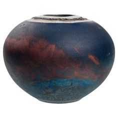 a blue and brown vase sitting on top of a white table