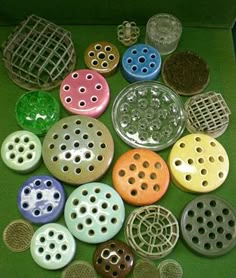 many different colored buttons in a box on a green surface with metal grates around them