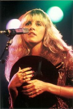 a woman holding a guitar in front of a microphone