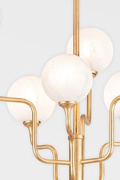 a brass chandelier with five white glass globes