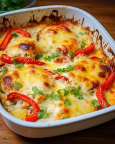 a casserole dish with red peppers and cheese in it on a wooden table