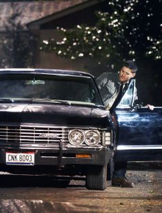 a man leaning out the window of a black car