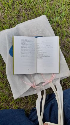 an open book sitting on top of a white cloth next to a pair of jeans