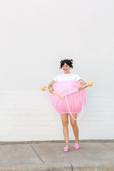 a woman in pink is holding a large ball of yarn