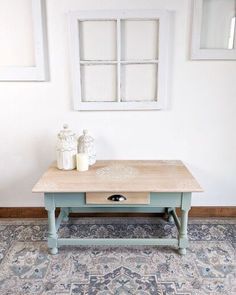 a coffee table with two candles on it in front of a white wall and blue rug