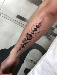 a person with a tattoo on their arm that has planets and stars in the middle