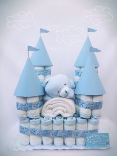 a blue castle cake with a teddy bear in the center and other items around it