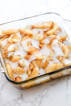 a casserole dish filled with bananas and white icing on a marble counter